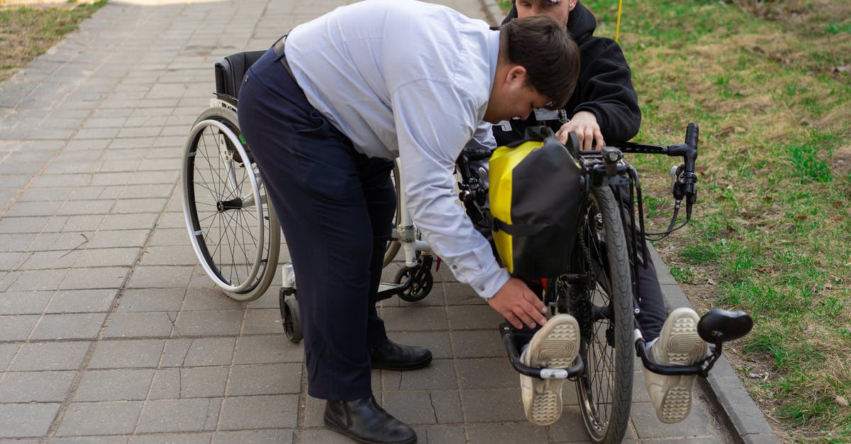 Electric wheelchairs hire in Cologne - A Man in Blue Long Sleeve Shirt Assisting a Man Riding Electric Wheelchair