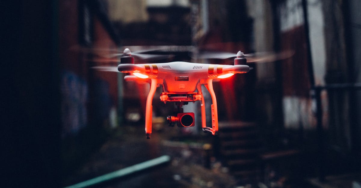 Electronic devices security on airplanes - Red glowing modern drone flying in air on blurred background of gloomy industrial street