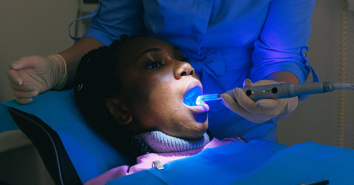 Electronic medical devices through British airport security - African American woman sitting in dental chair and receiving treatment with curing light from crop doctor