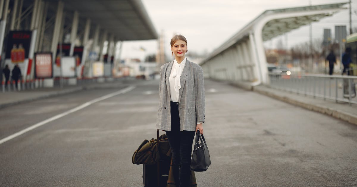 Emirates International Flight and carry-on baggage. Can I take a laptop backpack in addition to the one carry-on bag? - Happy female traveler walking on airport street with luggage