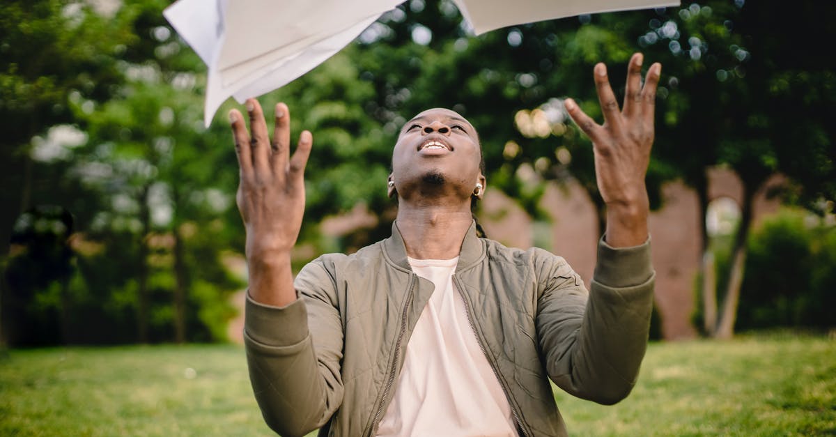 Entering air ticket costs in a UK Visa application - Content black remote worker throwing work papers in air happy to get rid of boring paperwork while sitting in green park with laptop