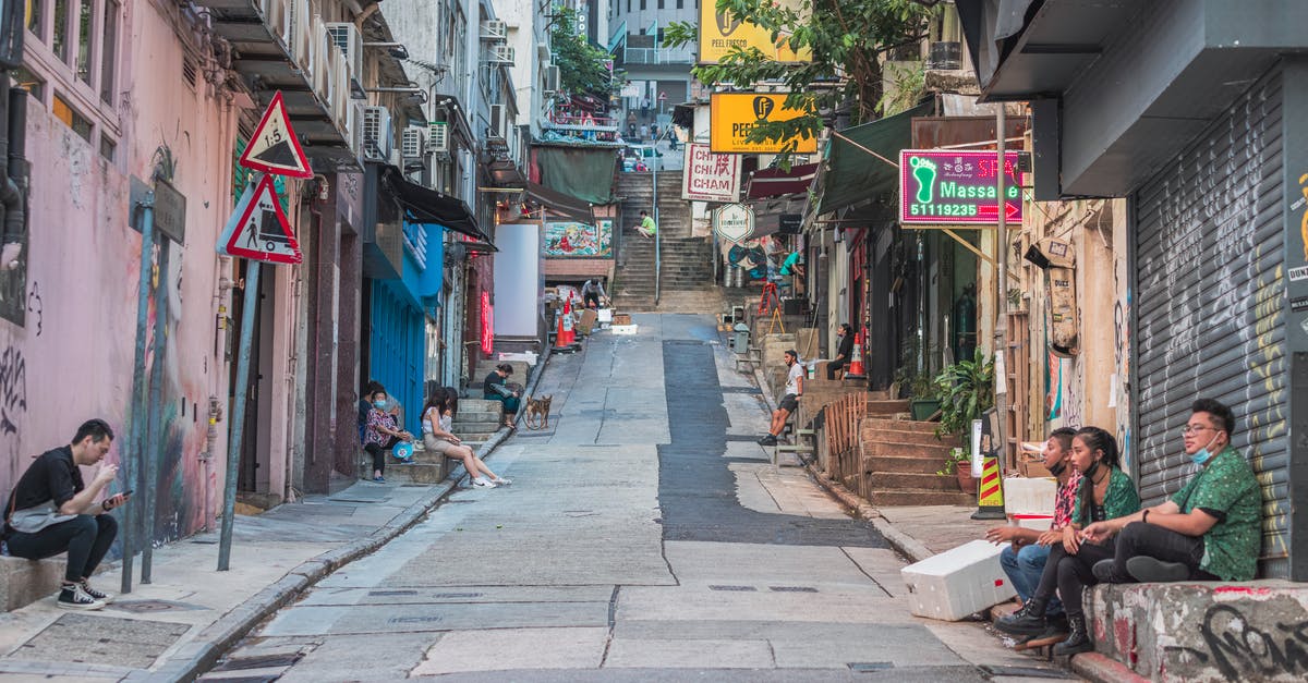 Entering China from Hong Kong without a Hong Kong visa - Man in Black Jacket Sitting on Brown Wooden Bench Near Store