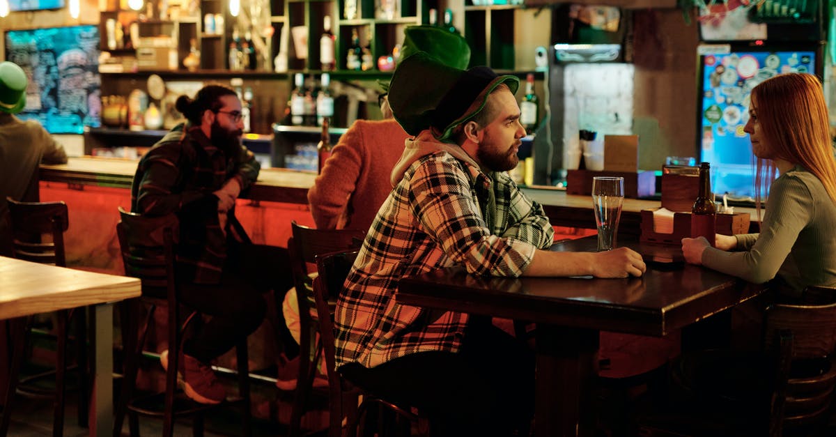 Entering Colombia with Alcohol - Man in Brown and White Plaid Dress Shirt Wearing Green Knit Cap Sitting on Chair