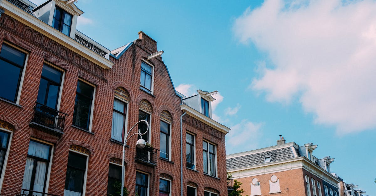 Entering Schengen area twice within 90 days - Low angle brick facade of old residential building with balconies and tile roof against blue sky on sunny day