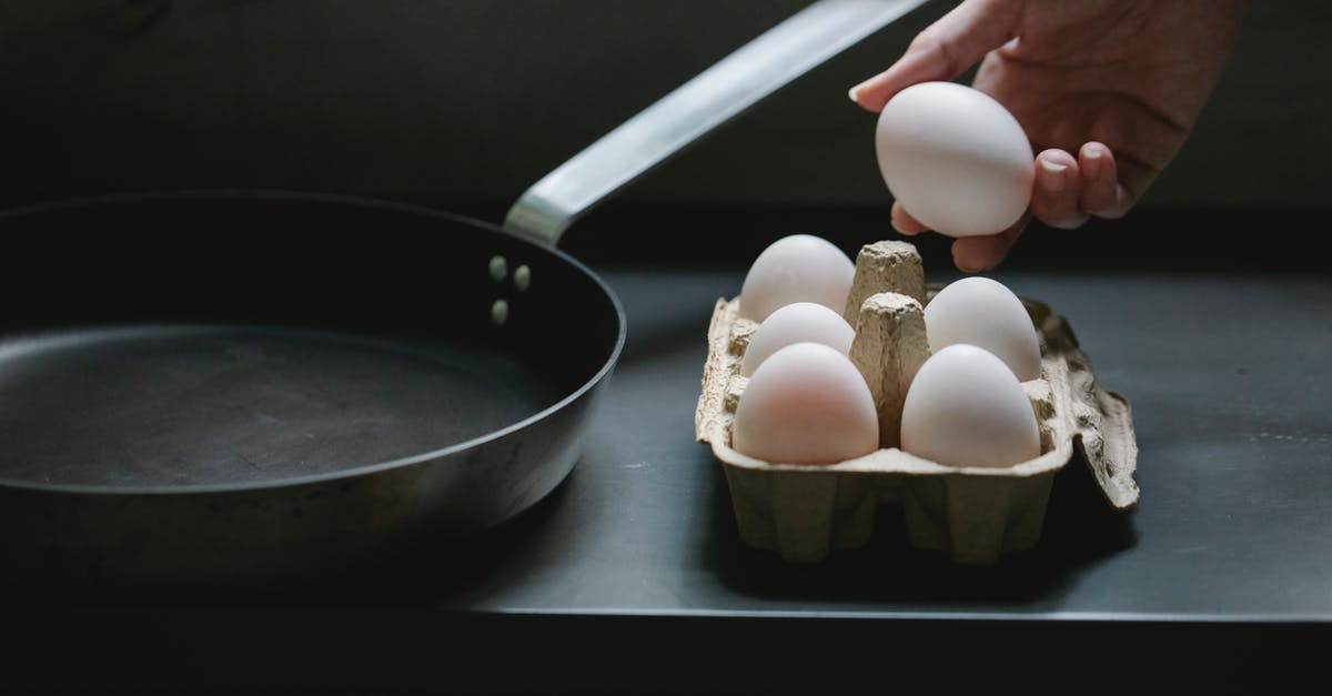 Entering the EU with a packaged netbook, duty and taxes - High angle of crop anonymous housewife with uncooked chicken egg from container placed near pan