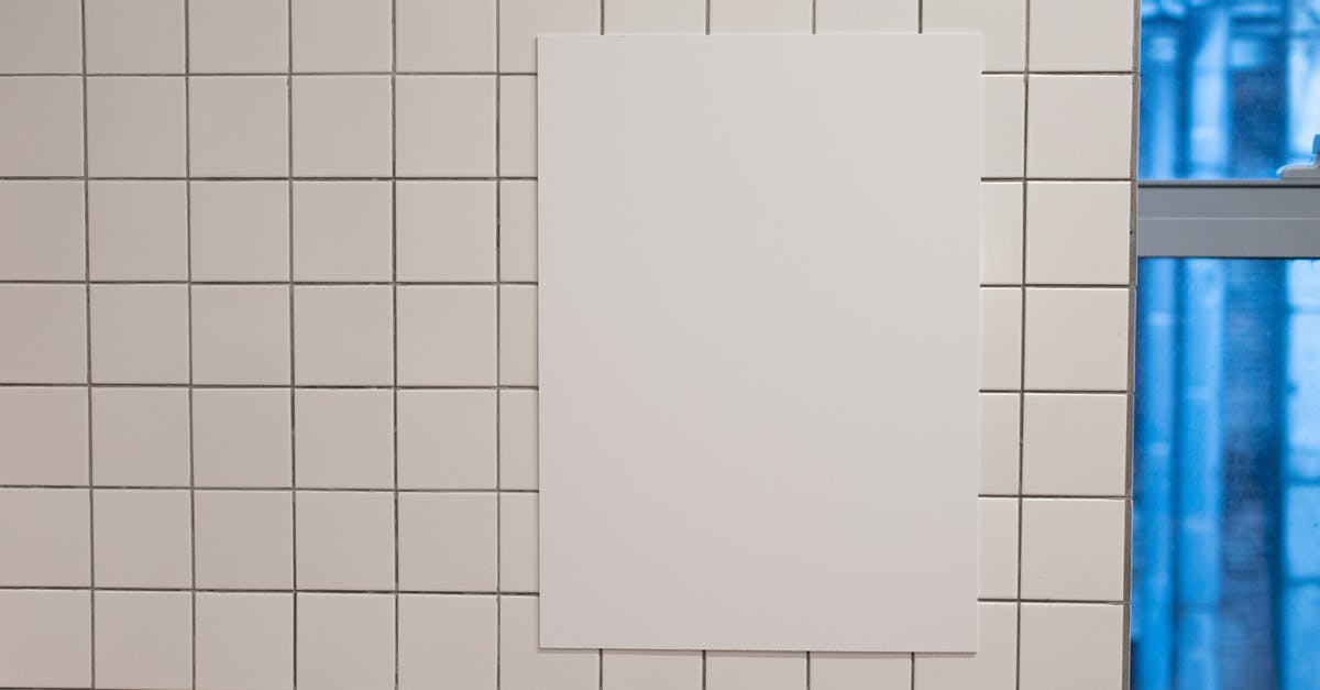 Entry requirements for arrival from space - Blank white placard hanging on wall covered with white tiles inside of building