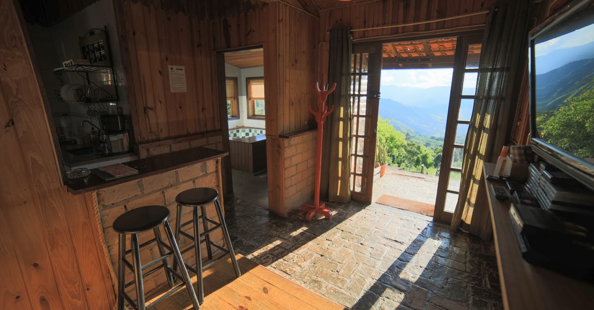 Entry to lounges at Addis Ababa airport? - Interior of rustic house with wooden walls and doorway overlooking green trees in sunlight growing in suburb area on summer day