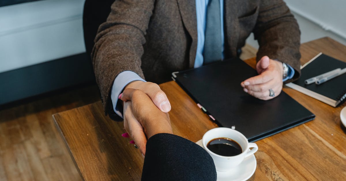 ethnic-related questions by immigration officer - Crop businesspeople making deal during workday