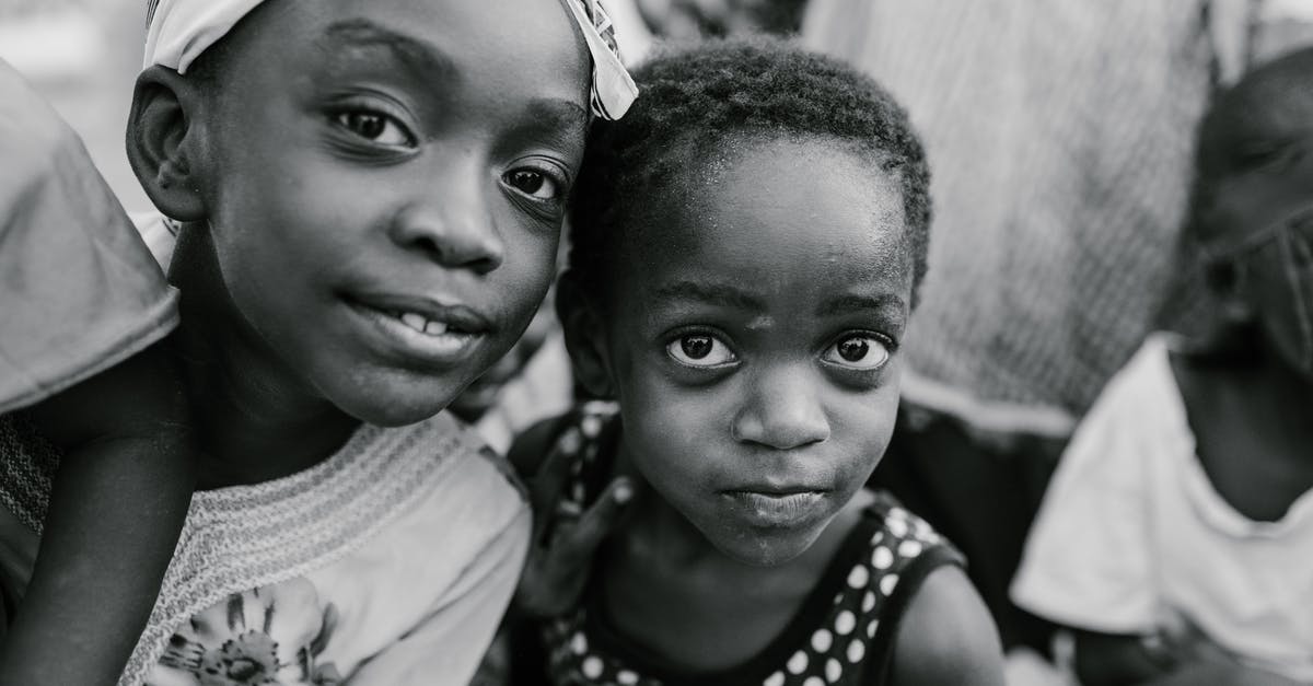 Etiquette when staying with an indigenous community - Black and white glad children in casual clothes standing on authentic town street and looking at camera with curiosity