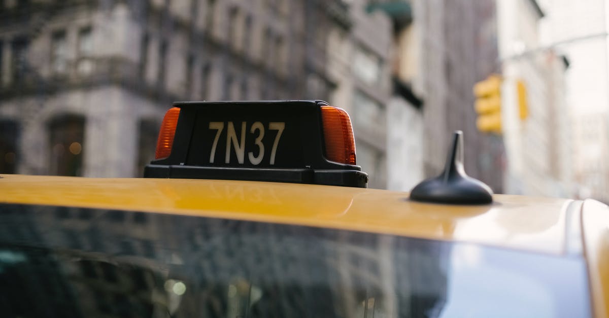 EU roaming when calling a number outside the EU? - Sign on roof of yellow cab with numbers and letter located in city on street with residential buildings on blurred background