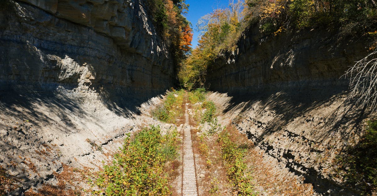 Euro Rail Pass in non-native country - Perspective view of rural railway running through rough rocky ravine in mountainous terrain on sunny summer day