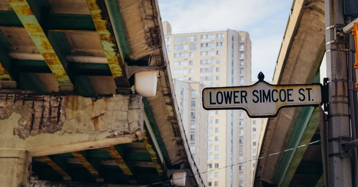 Europe: differences between colours of highway road-signs - Street sign placed on pole between old overpasses