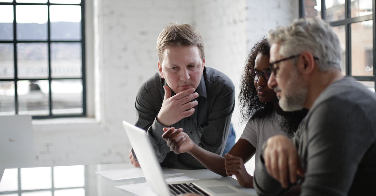 European bus tour companies for middle age people? [closed] - Concentrated serious multiracial people discussing details of creative project while sitting at table and using laptop in modern loft styled office