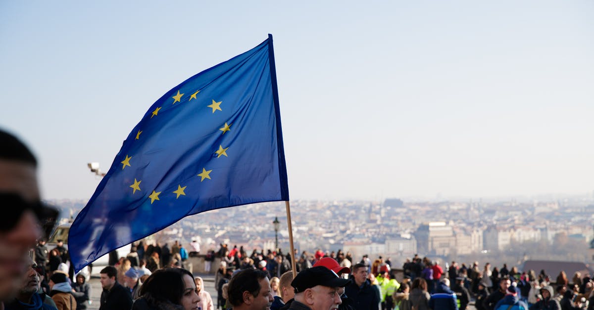 European citizen visiting Cuba while in US? - Crowd of people walking on street with waving flag of European Union Courtesy during protest in city against residential buildings