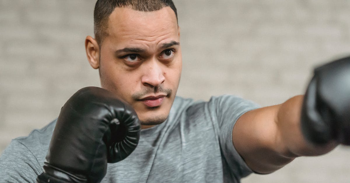 Eurostar train to Paris during a strike - Strong ethnic sportsman in boxing gloves performing punching technique while looking forward during training on blurred gray background