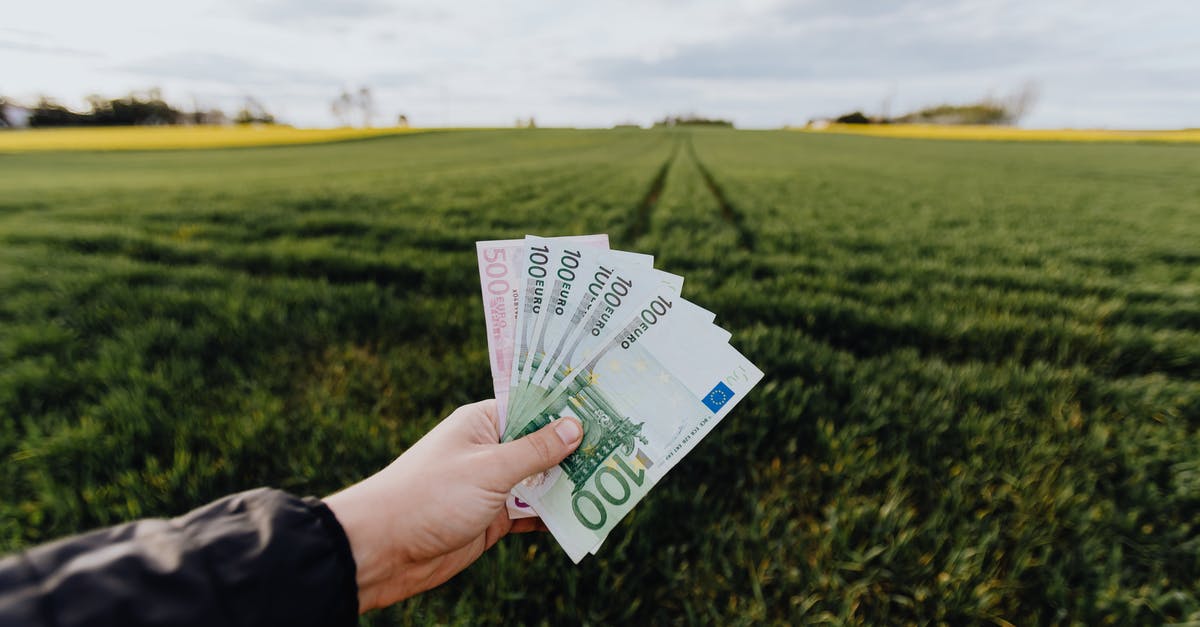 Exchanging Albanian money into euros outside Albania - Crop farmer showing money in green summer field in countryside