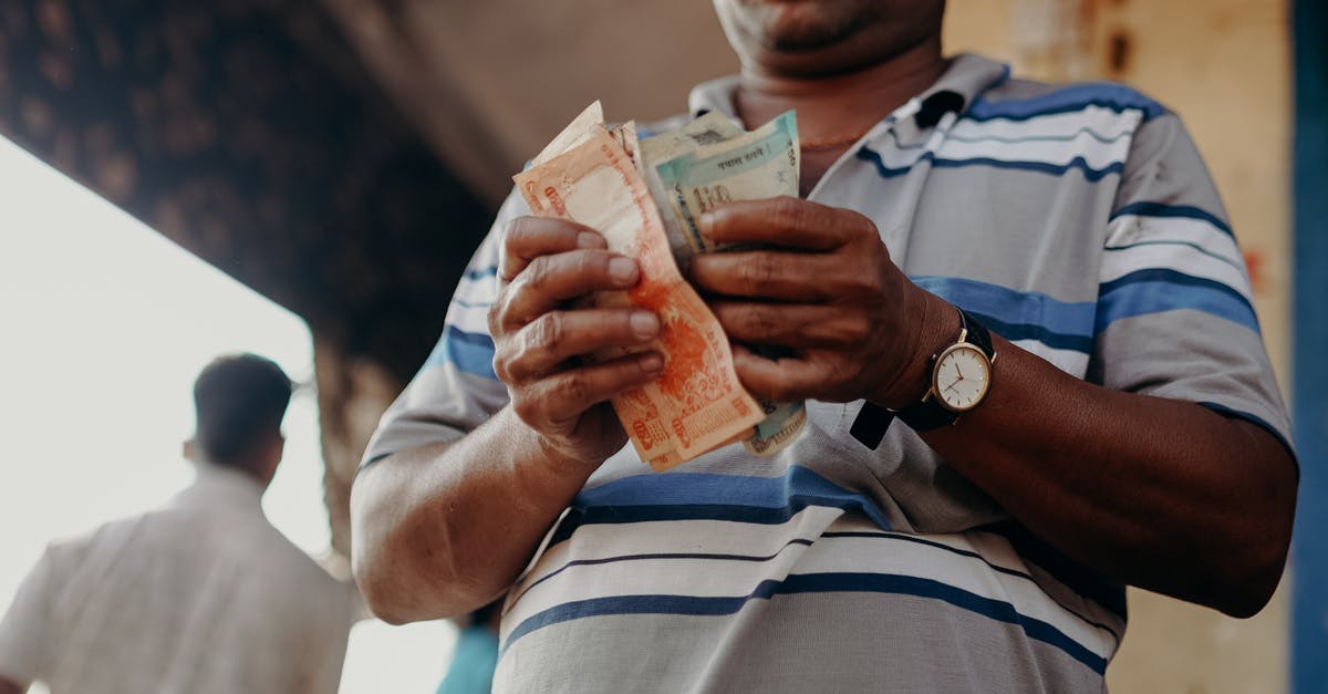 Exchanging demonetized Indian Rupee notes in Singapore - Man in Blue and White Stripe Polo Shirt Holding Banknote