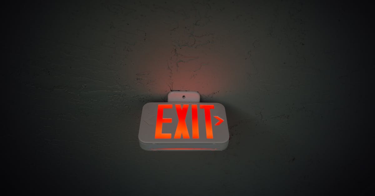 Exiting Canada with another passport and exit information - From below of illuminated exit sign hanging on gray concrete ceiling in dark room