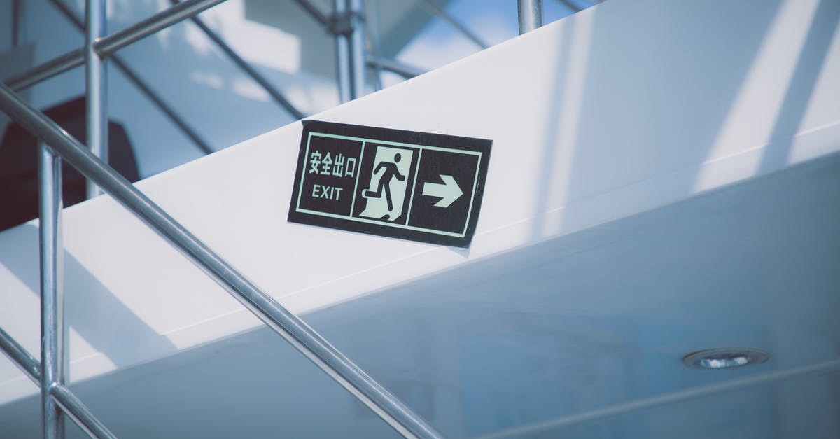 Exiting Canada with another passport and exit information - From below of rectangular signboard with EXIT title and symbol of running figure near stairs with handrail in modern house