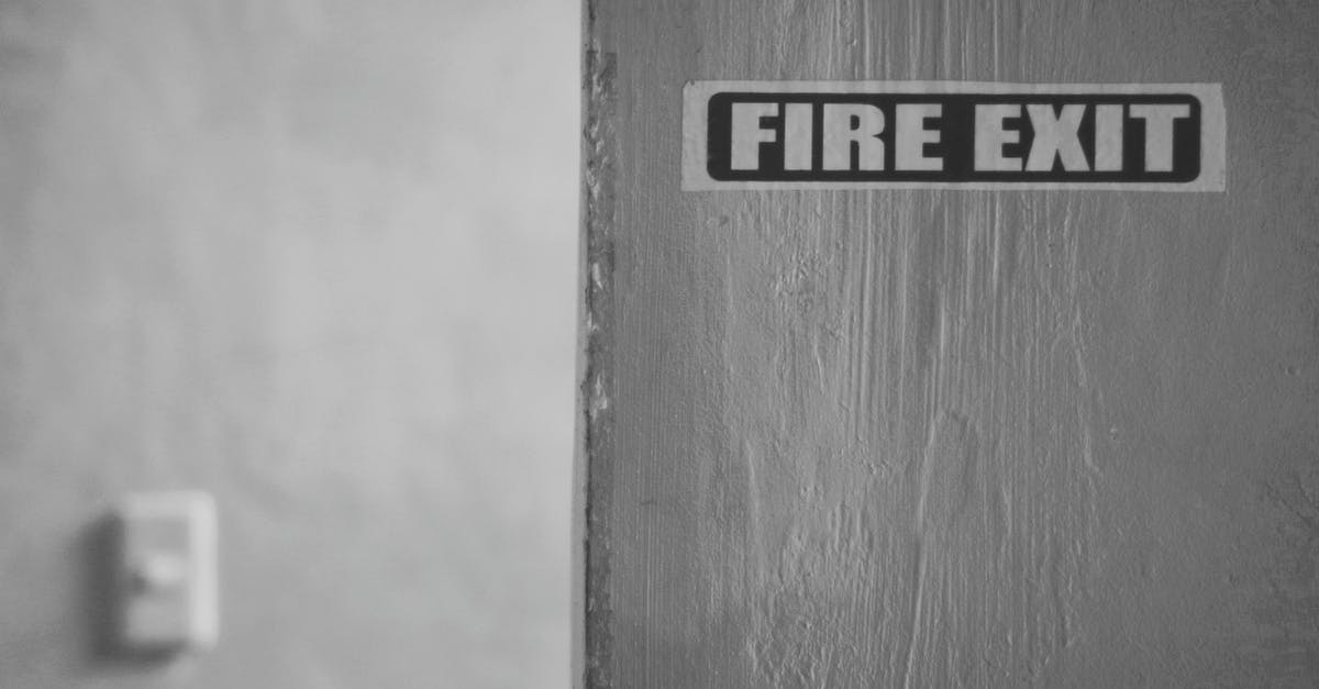 Exiting Canada with another passport and exit information - Black and white of wall with inscription Fire exit in room in daytime