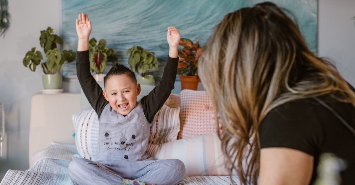 Expenditure in Poland - Forex Card doesn't have Złoty - Happy boy raising arms after winning card game sitting on bed with unrecognizable mother