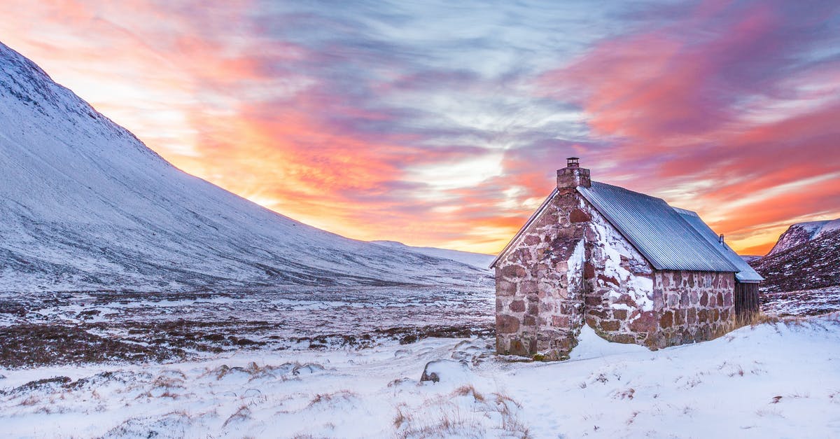 Experiencing Scotland in the Winters [closed] - Brown House Surrounded by Snow Covered Field Near Snow Covered Mountain Under Yellow Blue and Orange Sunset