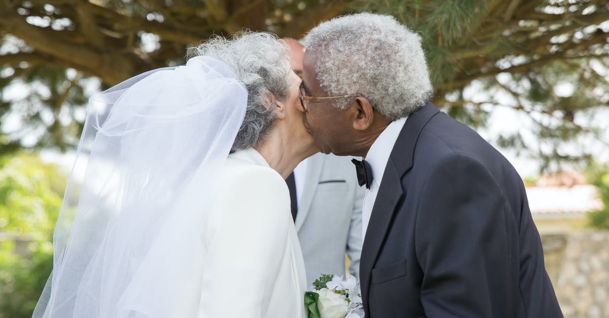 Extending a layover to the next day - Man in Black Suit Jacket Kissing Woman in White Wedding Dress