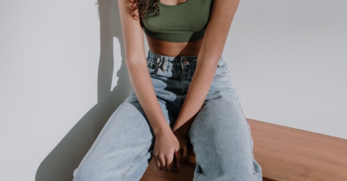 Extending Visa from Philipines bureau of Imigration - Woman in Green Tank Top and Blue Denim Jeans Sitting on Brown Wooden Chair