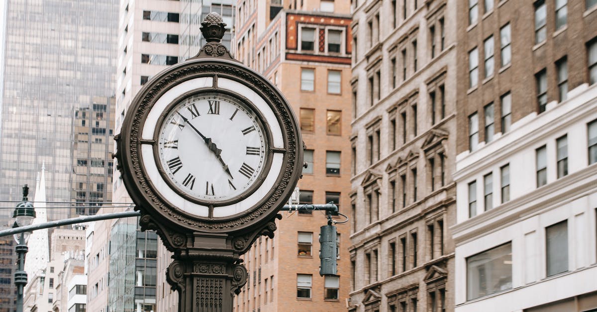 Extension of USA B2 visa 2nd time - Vintage street clock on pillar located near residential buildings and skyscrapers in downtown of New York city in financial district