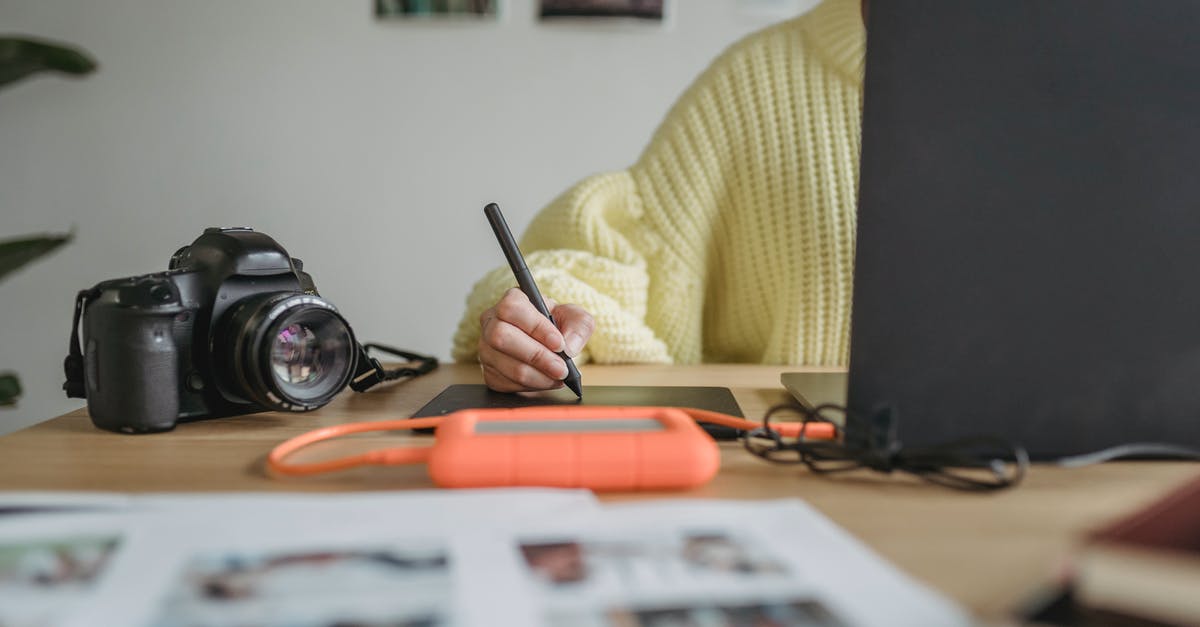 External Carry-On Attachments - Crop anonymous woman using graphic tablet while editing photos on netbook at table with photo camera and blurred printed photos