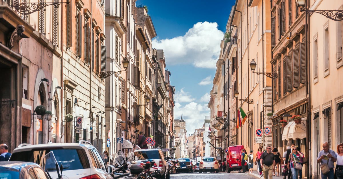 Factors to consider when travelling by car with a 1.5 year old baby in Europe? - Narrow street with cars and motorcycles parked near historic buildings located in city in Europe and with people walking outside under blue sky in summer sunny day