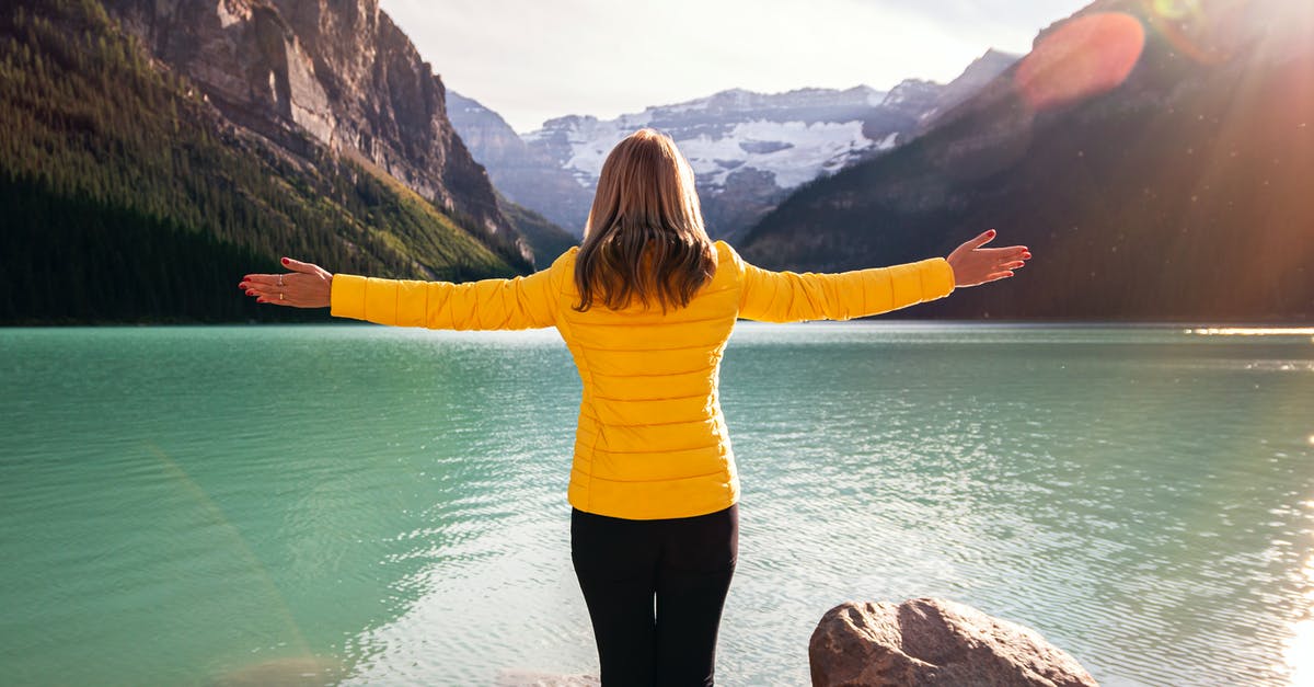 Fairmont Banff Springs vs Fairmont Chateau Lake Louise [closed] - Woman in Yellow Long Sleeve Shirt and Black Pants Standing on Rock Near Body of Water
