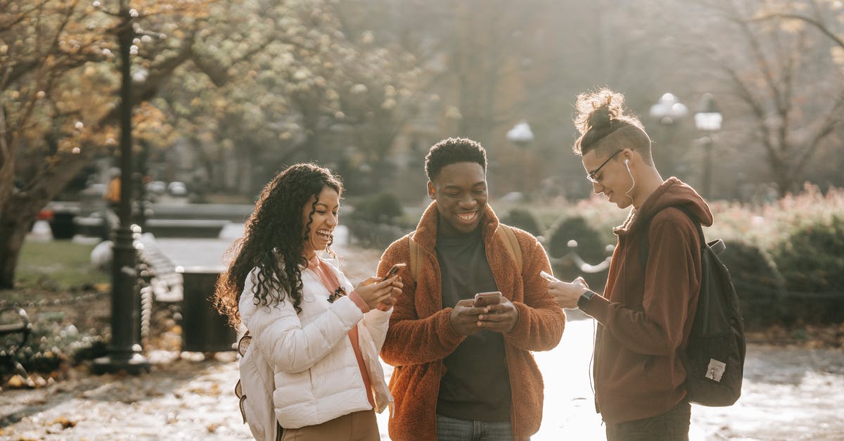 Fall asleep in terminal and miss connection fight: recover change fee - Multiracial positive male and female students using smartphones in city park