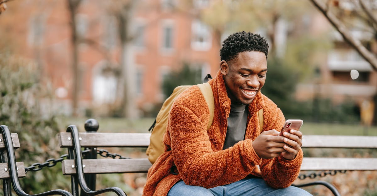 Fall asleep in terminal and miss connection fight: recover change fee - Delightful African American man surfing modern cellphone in city park