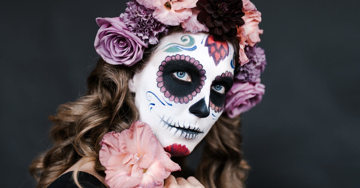 Fall events in Madrid - Young female with sugar skull make up and hair decorated with flowers for celebrating Halloween