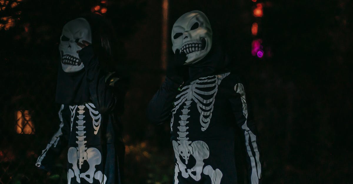 Fall events in Madrid - Unrecognizable persons dressed in costumes of skeleton standing on dark street