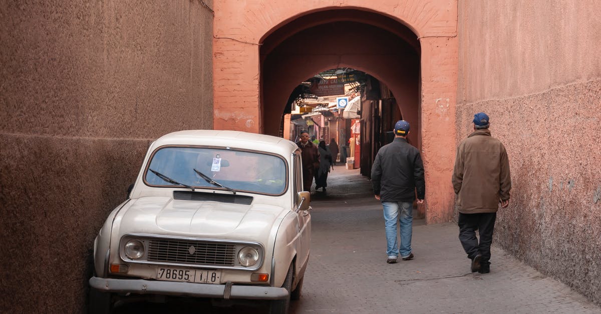 Fastest cheap way to get from Morocco to Algeria? - Unrecognizable men walking on street near arched passage