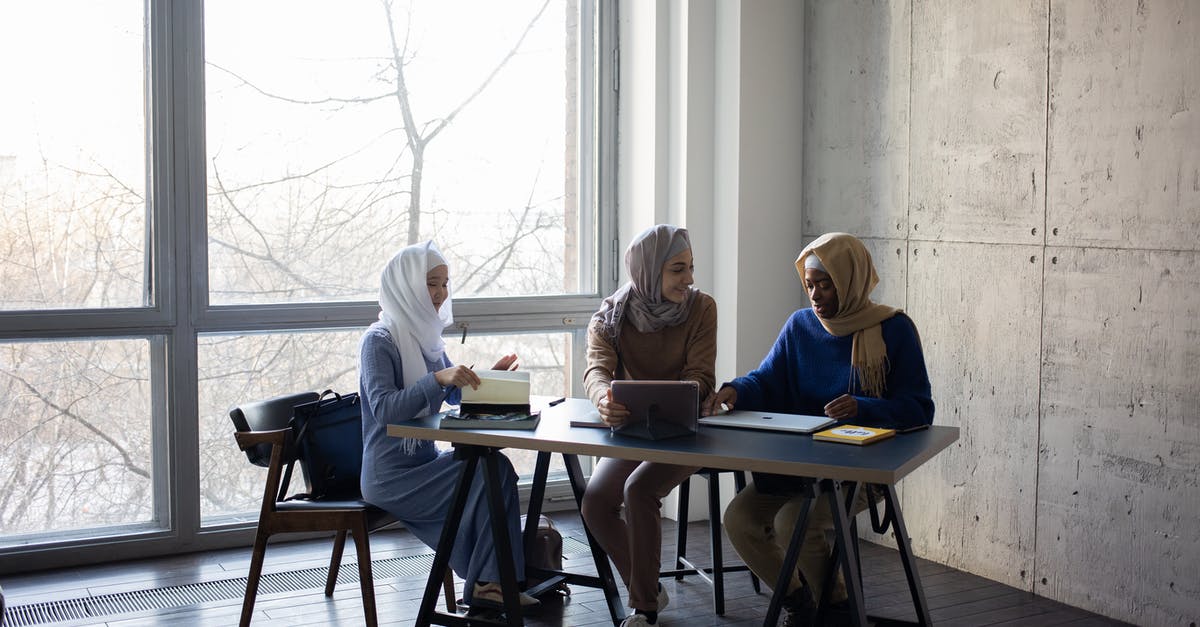 Filipino national getting a visa via a British partner - Diverse Muslim businesswomen talking about job at table with tablet