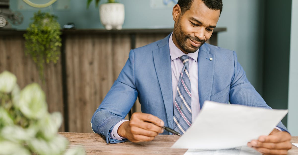 Financial proof papers for schengen visa - Man in Blue Suit Jacket Holding White Paper and Ballpen