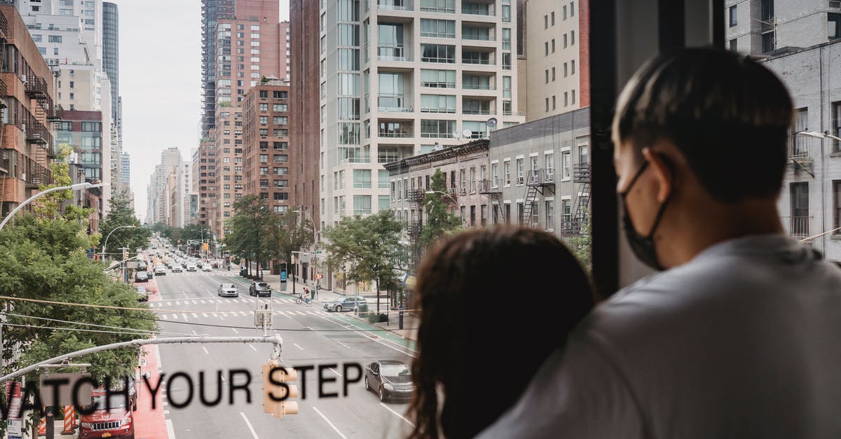 Finding a nice, secluded cabin in the U.S. wilderness - Back view anonymous romantic couple hugging and observing urban modern New York street while riding ropeway cabin