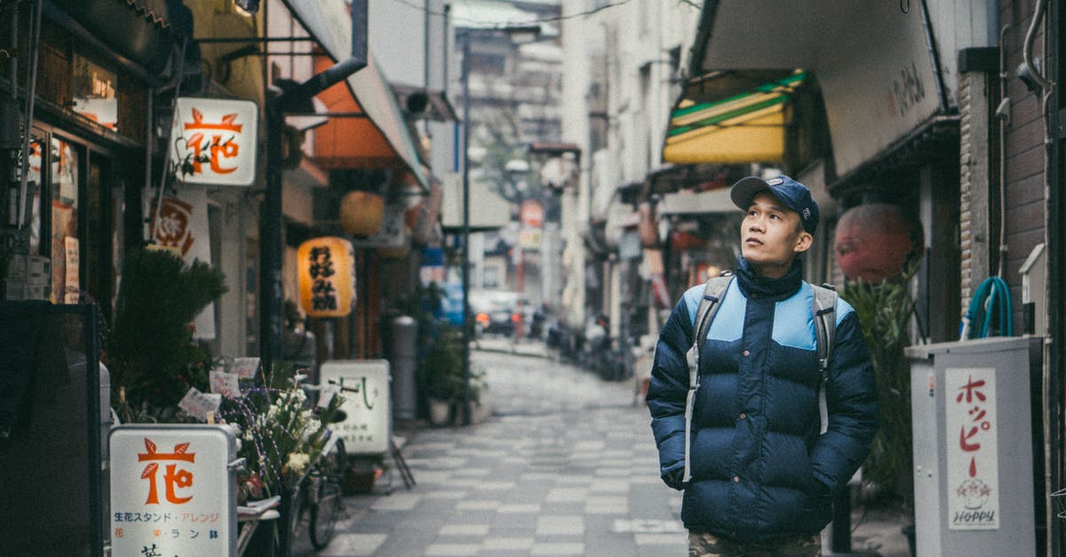 Finding non-smoking restaurants in Japan - Man Walking on Grey Concrete Alley Surrounded by Buildings