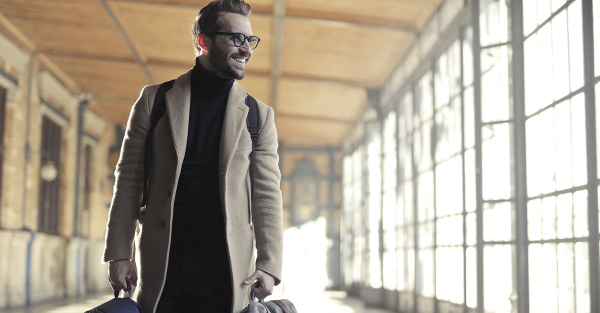 Finding the train station at Copenhagen airport - Man in Brown Robe Carrying Bag Smiling