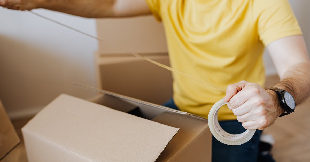 Flight itinerary/time/date change - Crop man with cardboard boxes while packing belongings