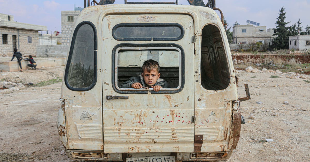 Flight path over a war zone, such as Syria and Iraq in 2015 - Boy sitting in broken car