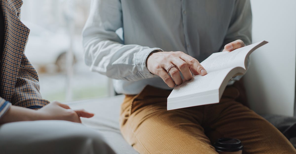 Flight/booking code explanation - Man in White Dress Shirt and Brown Pants Sitting on White Chair Reading Book