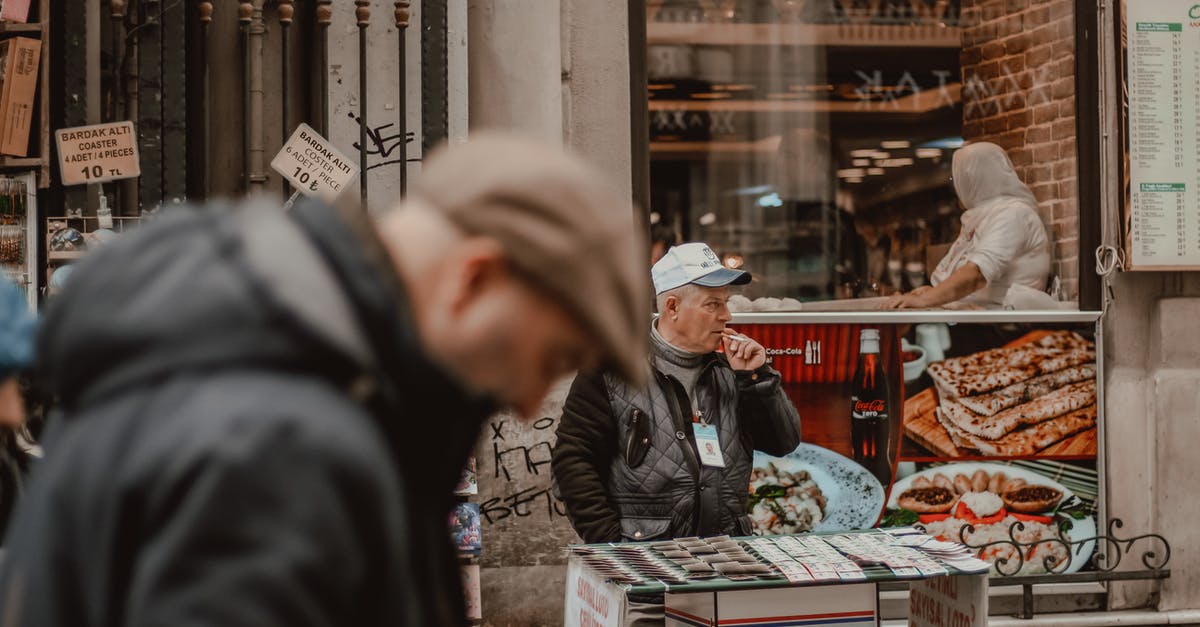 Florence - Do those "Authorised seller" signs at the stores selling leather goods mean anything? - Senior male smoking while standing on street market and selling local souvenirs during work day