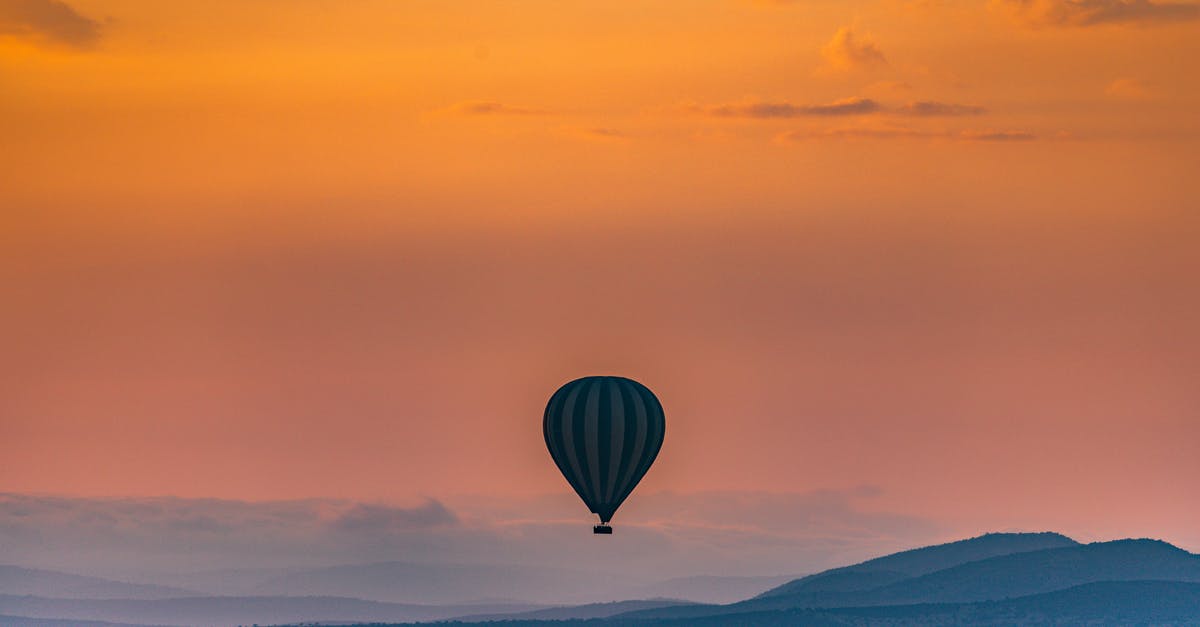 Flying between Tanzania and Madagascar - Bright sunset over mountains and hot air balloon flying above wild animals