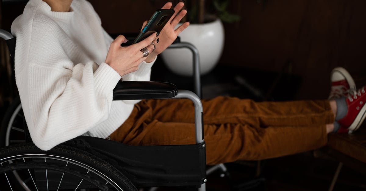 Flying for the first time tomorrow, is a physical boarding pass required or is the app enough? - Side view of crop unrecognizable female millennial with disability sitting in wheelchair and browsing mobile phone