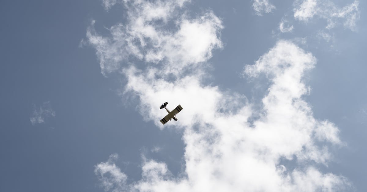 Flying from IAD→YTZ→YHZ—where do I clear Canadian customs? - From below of airplane with wings flying high in air on sky with white clouds during flight on sunny day