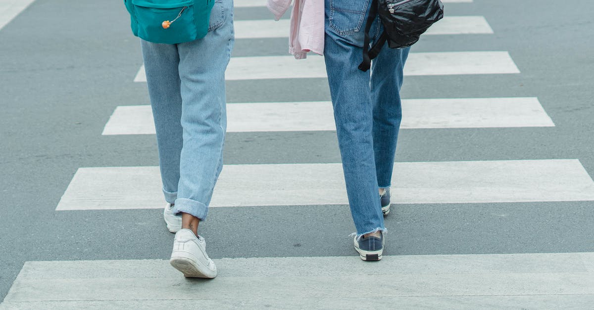 Flying together but parting ways later on. - Unrecognizable women wearing jeans crossing city street